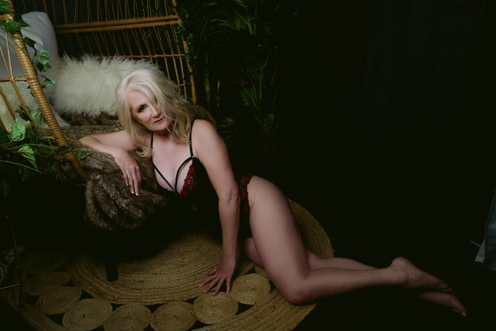 A woman in black lingerie poses gracefully in a hammock for boudoir photography.