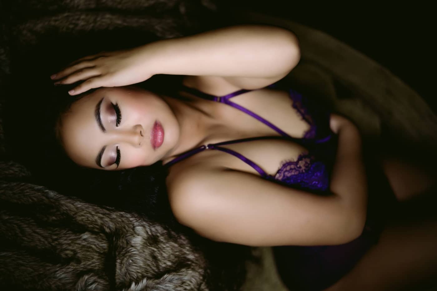 A woman lying down with her eyes closed during a Northern Virginia Boudoir Photography session.