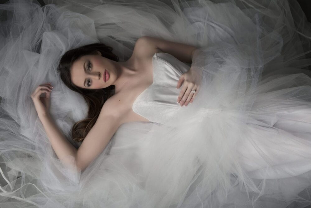 beautiful woman laying on the floor wearing a tulle wedding gown