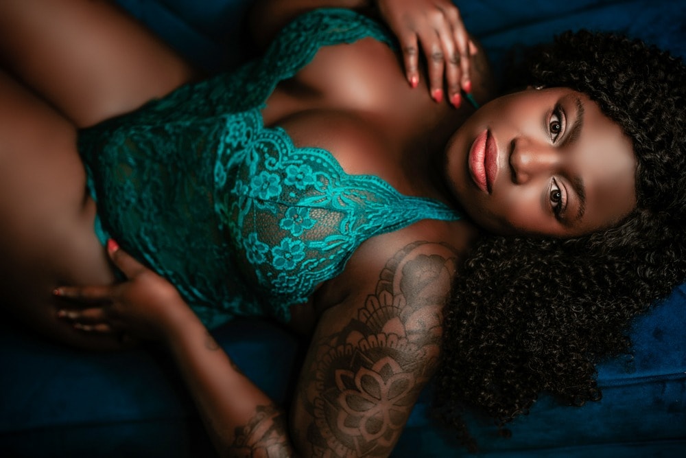 A woman with tattoos laying on a blue couch.