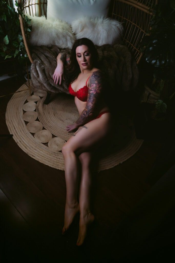A woman in red lingerie laying on a rug.