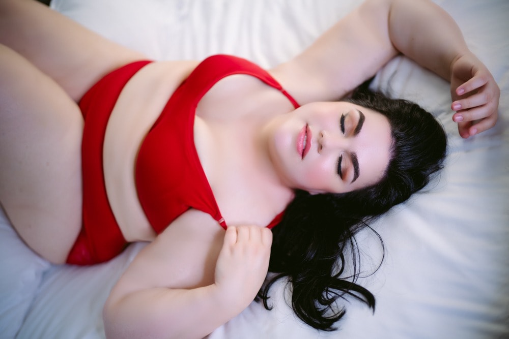 A woman in a red lingerie laying on a bed.