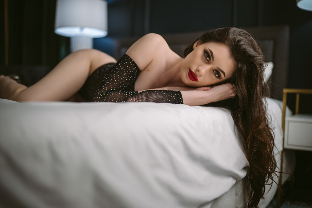 A beautiful woman undergoing Northern Virginia boudoir photography on a bed.