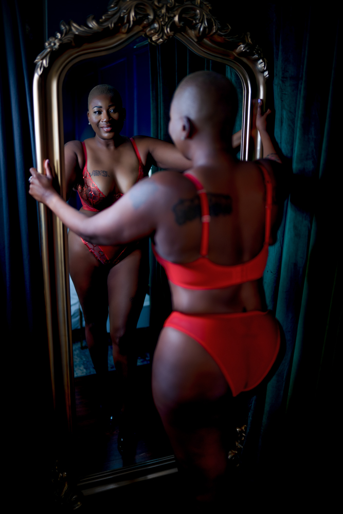 A woman in red lingerie poses in front of a mirror for Northern Virginia Boudoir Photography.